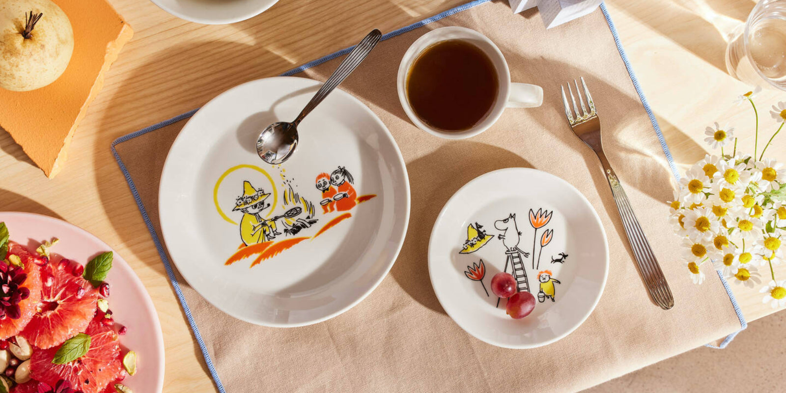 Arabia x Red Cross Moomin dinnerware displayed on a layer table